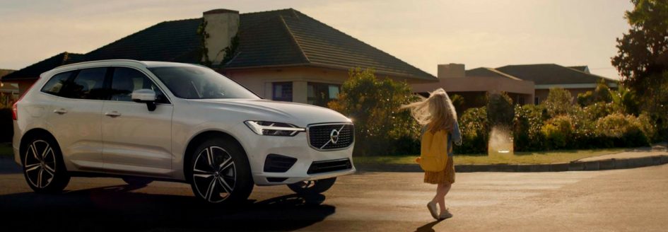White Volvo XC60 parked in front of a house at sunset with girl walking in front of it