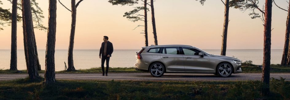 Silver 2019 Volvo V60 parked in a wooded area next to a lake.